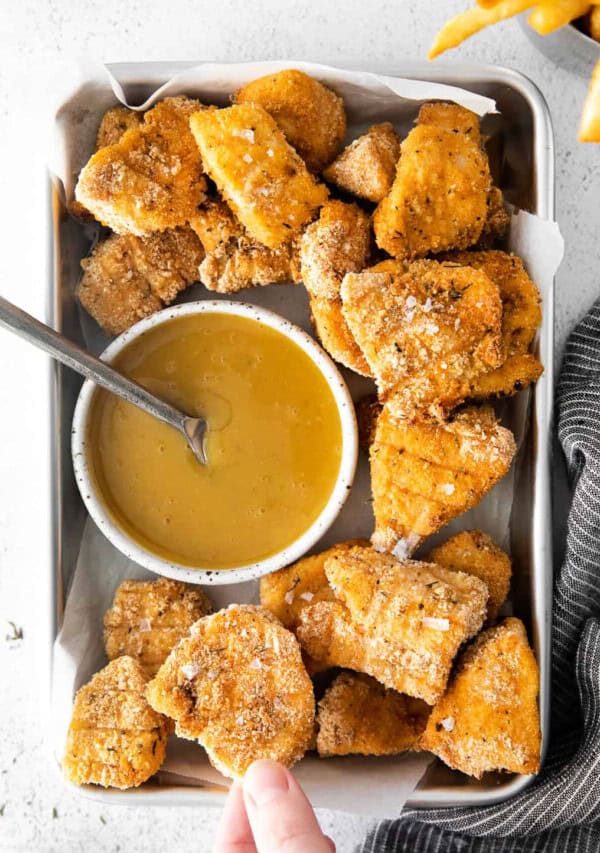 Fried chicken nuggets in a tray with dipping sauce.