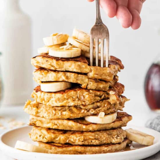 A stack of pancakes with bananas and syrup on a plate.