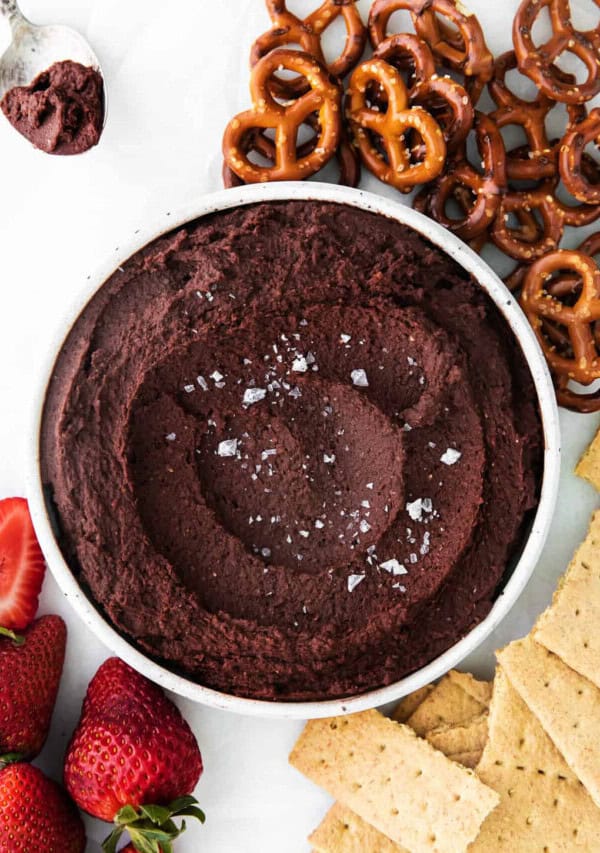 A bowl of chocolate hummus with strawberries and pretzels.