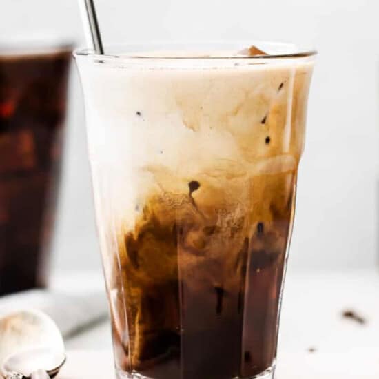 An iced coffee in a glass with a spoon.