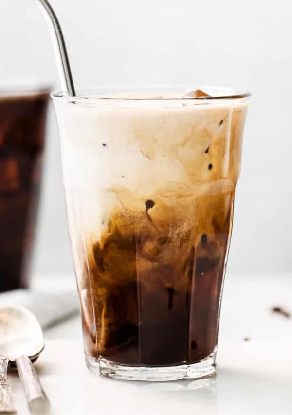 An iced coffee in a glass with a spoon.