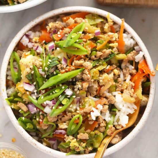 A bowl of asian stir fry with rice and vegetables.