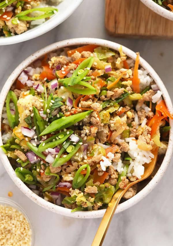 A bowl of asian stir fry with rice and vegetables.