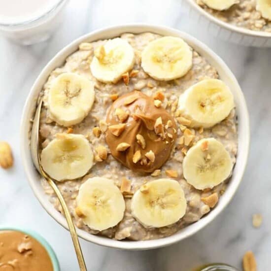 A bowl of oatmeal with peanut butter and banana slices.