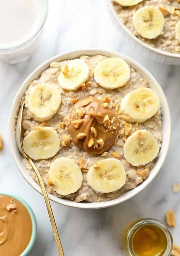 A bowl of oatmeal with peanut butter and banana slices.