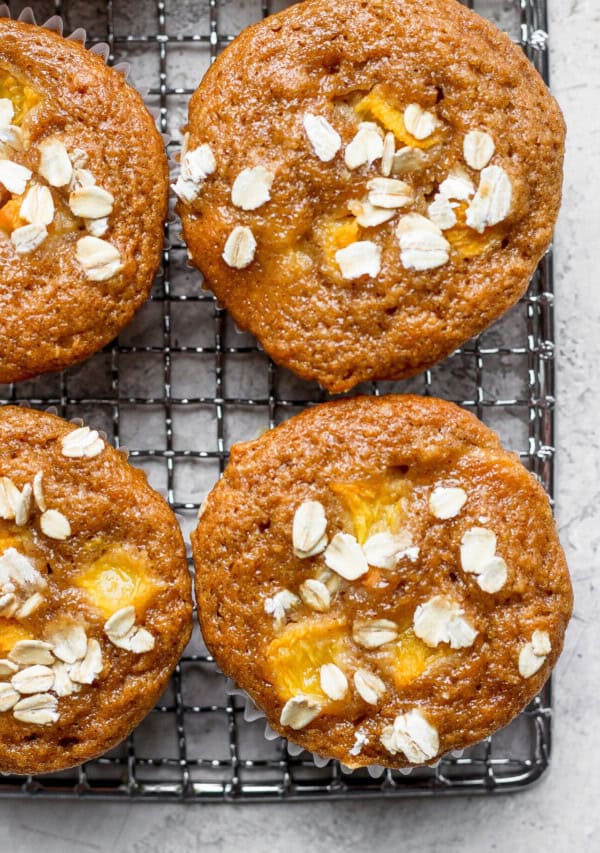 Peach muffins with oats on a cooling rack.