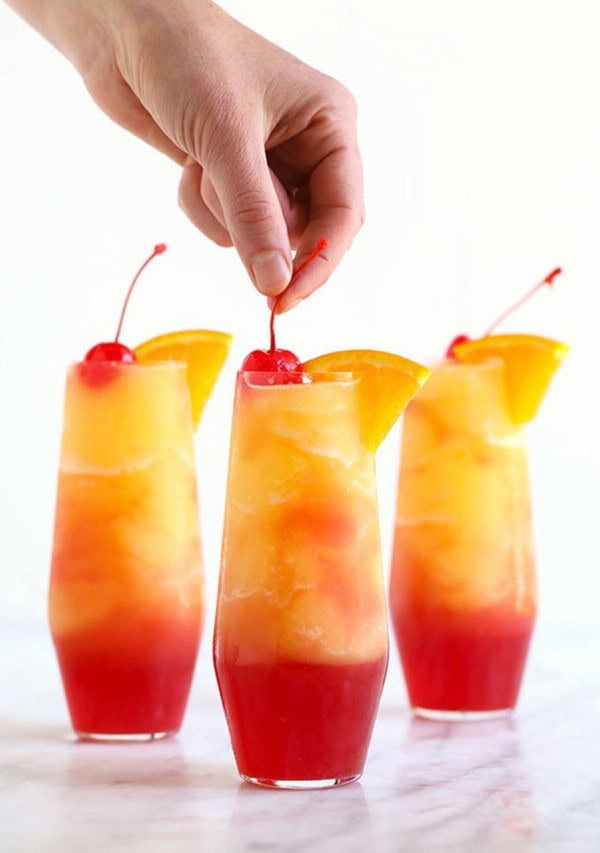 A person is putting a cherry into a drink.