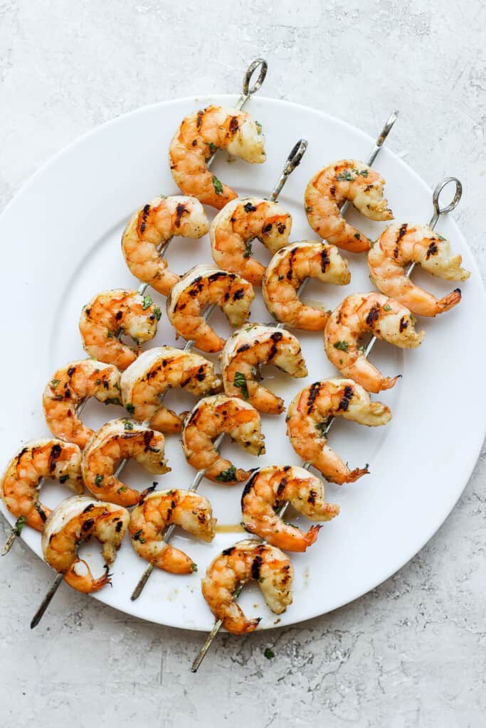 Grilled shrimp on skewers on a plate.