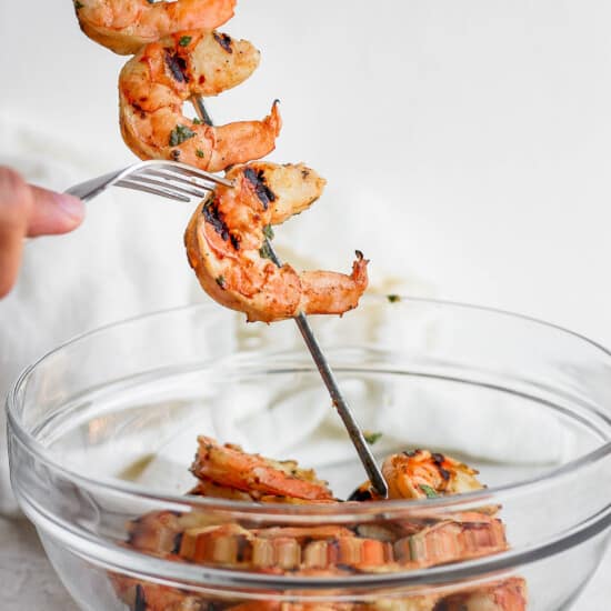 Grilled shrimp on skewers in a glass bowl.