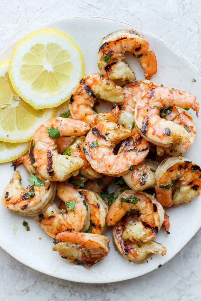 Grilled shrimp on a plate with lemon slices.
