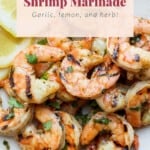 Grilled shrimp marinade with lemon and herbs on a white plate.