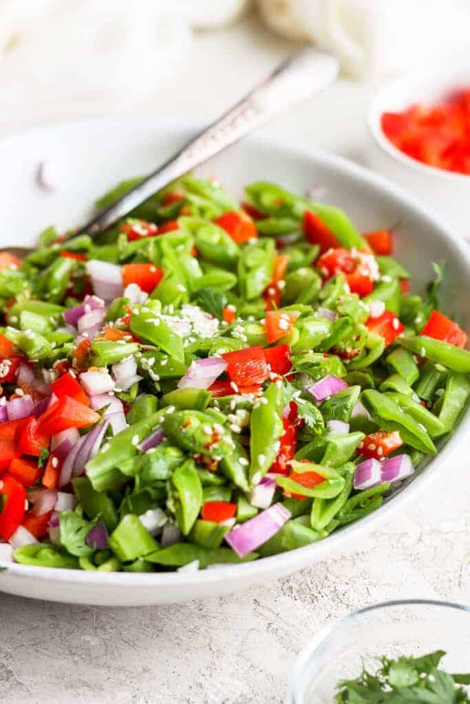 Ginger pea salad in a bowl topped with sesame seeds. 