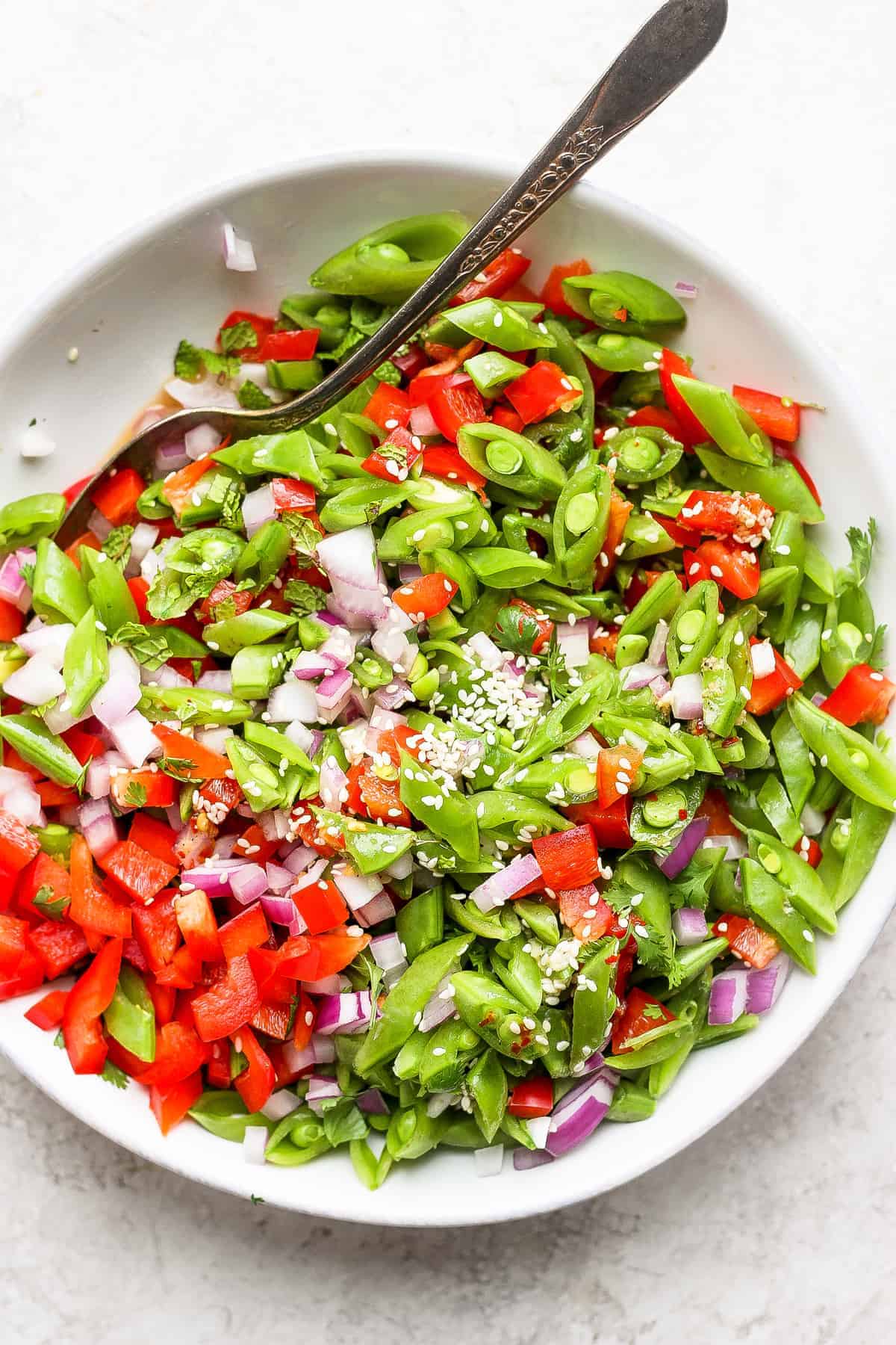 Ginger Pea Salad in a bowl topped with sesame seeds. 