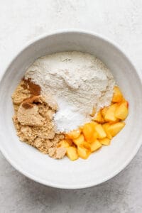 Peach crumble ingredients in a white bowl, perfect for peach muffins.