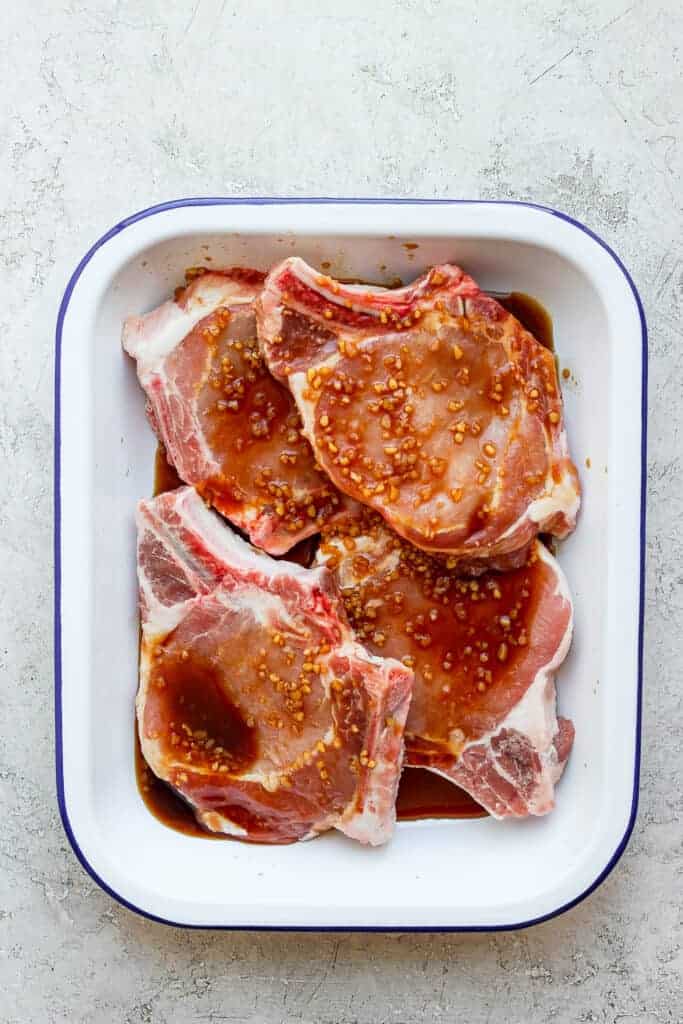 pork chops marinating in dish.