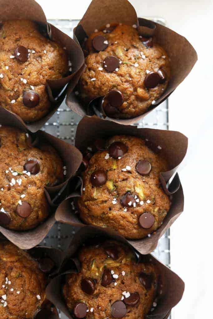 This zucchini muffin recipe is sweetened with banana, maple syrup, and coconut sugar and uses 100% white whole wheat flour. zucchini muffins on wire rack