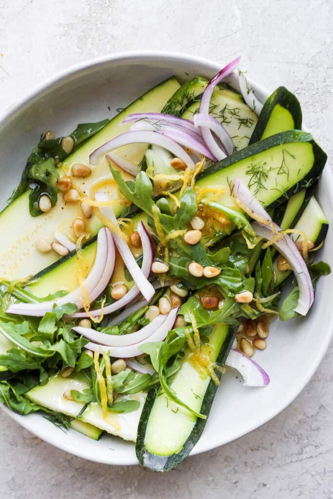 zucchini salad ingredients drizzled with a homemade salad dressing