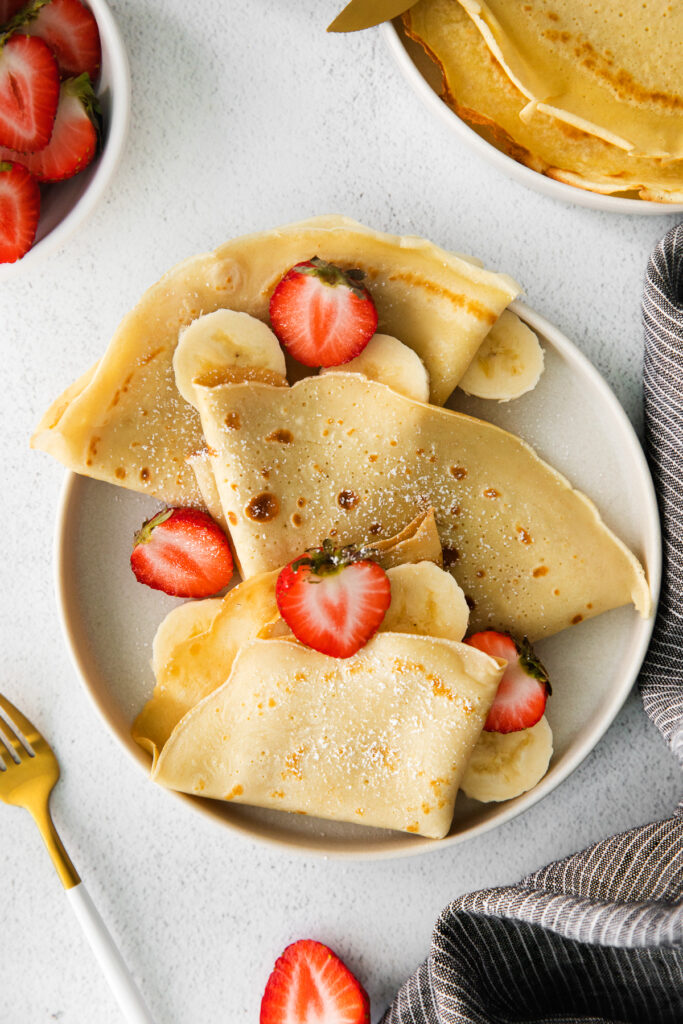 Crepes on a plate with strawberries and bananas. 