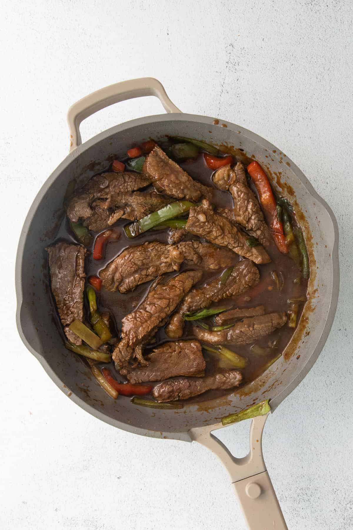 Pepper steak cooking in a fry pan.