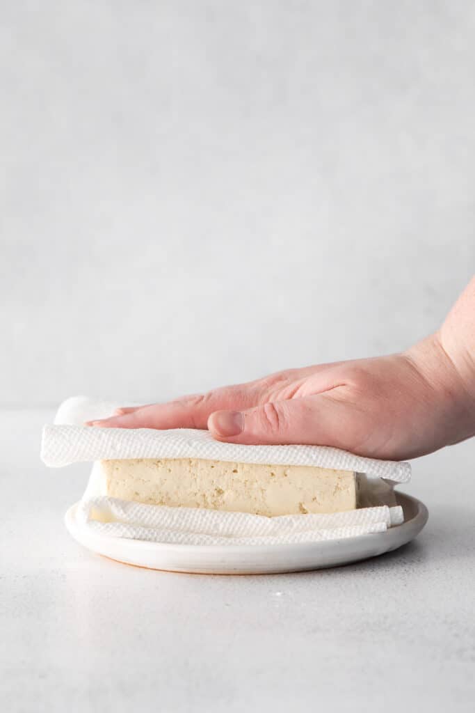 Removing moisture from tofu with a paper towel. 
