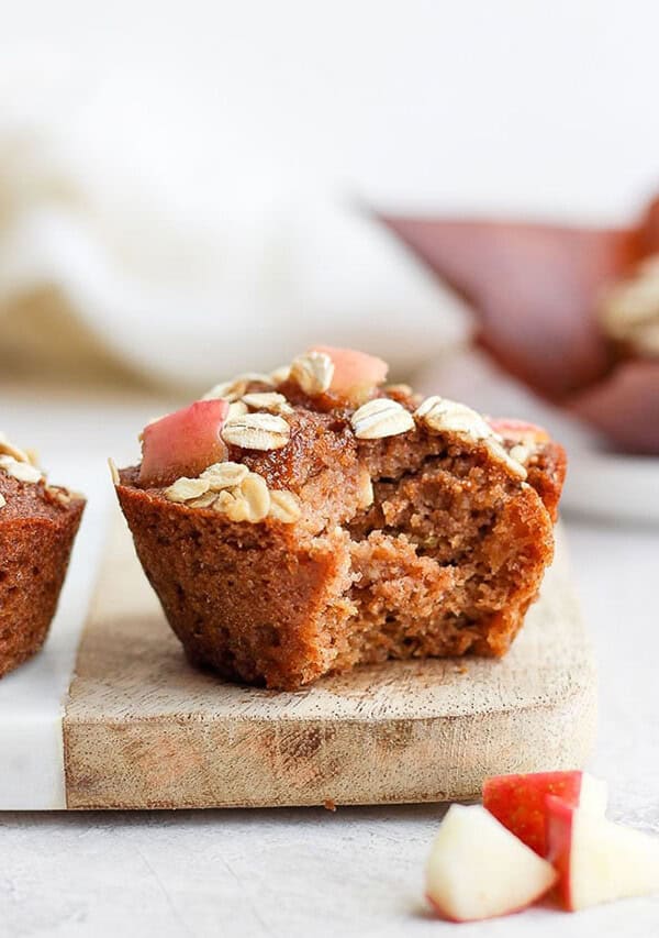 apple muffins on a cutting board with a bite taken out.