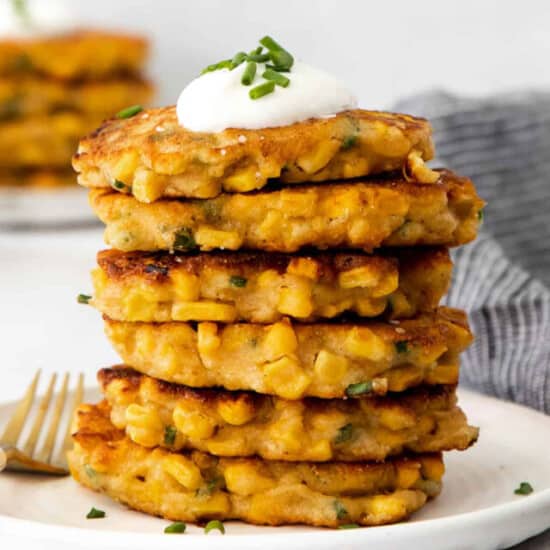 A stack of corn cakes with sour cream and chives.