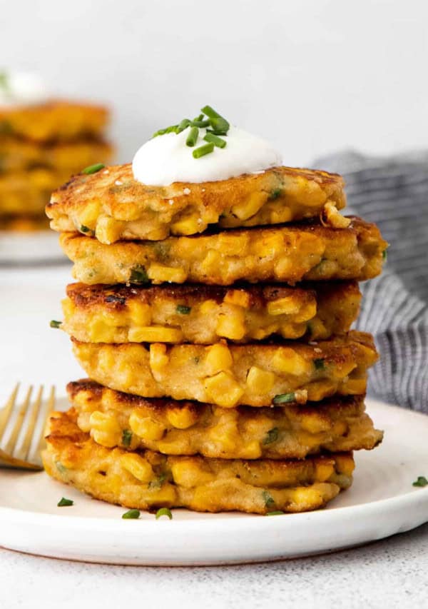 A stack of corn cakes with sour cream and chives.