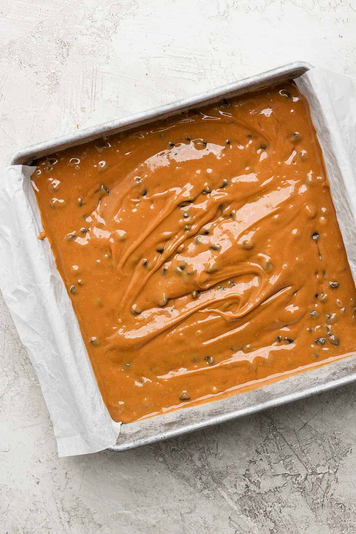 cookie dough freezer fudge spread into a square cake pan, ready to go into the freezer