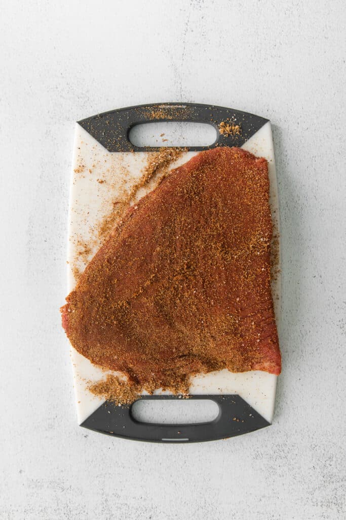flank steak with a dry rub on a cutting board