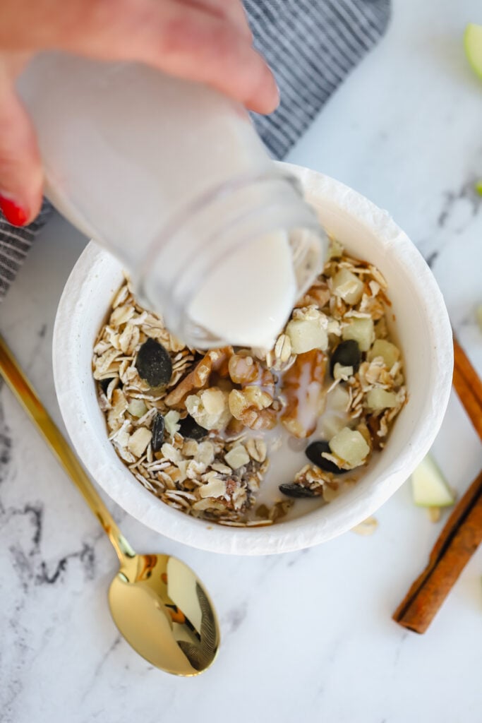 milk being poured over an oat bowl