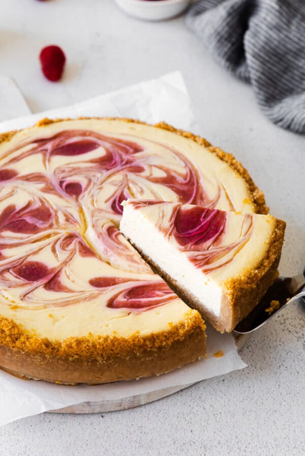 A raspberry swirl Greek yogurt cheesecake with a slice taken out.