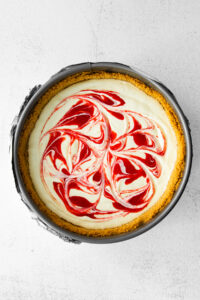 Greek yogurt cheesecake with red and white swirls on top.