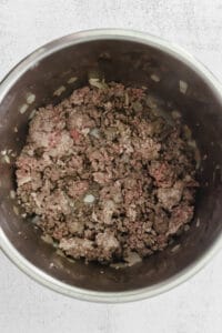 Bowl of instant pot chili with ground beef on a white surface.