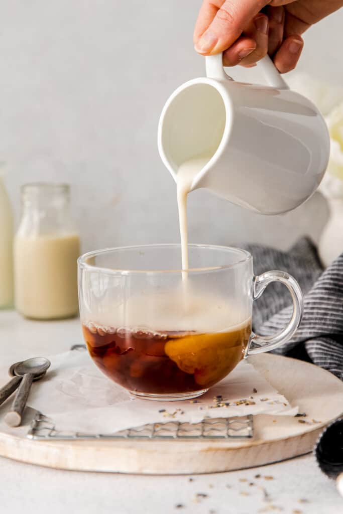 steamed milk being poured in a mug of earl grey tea