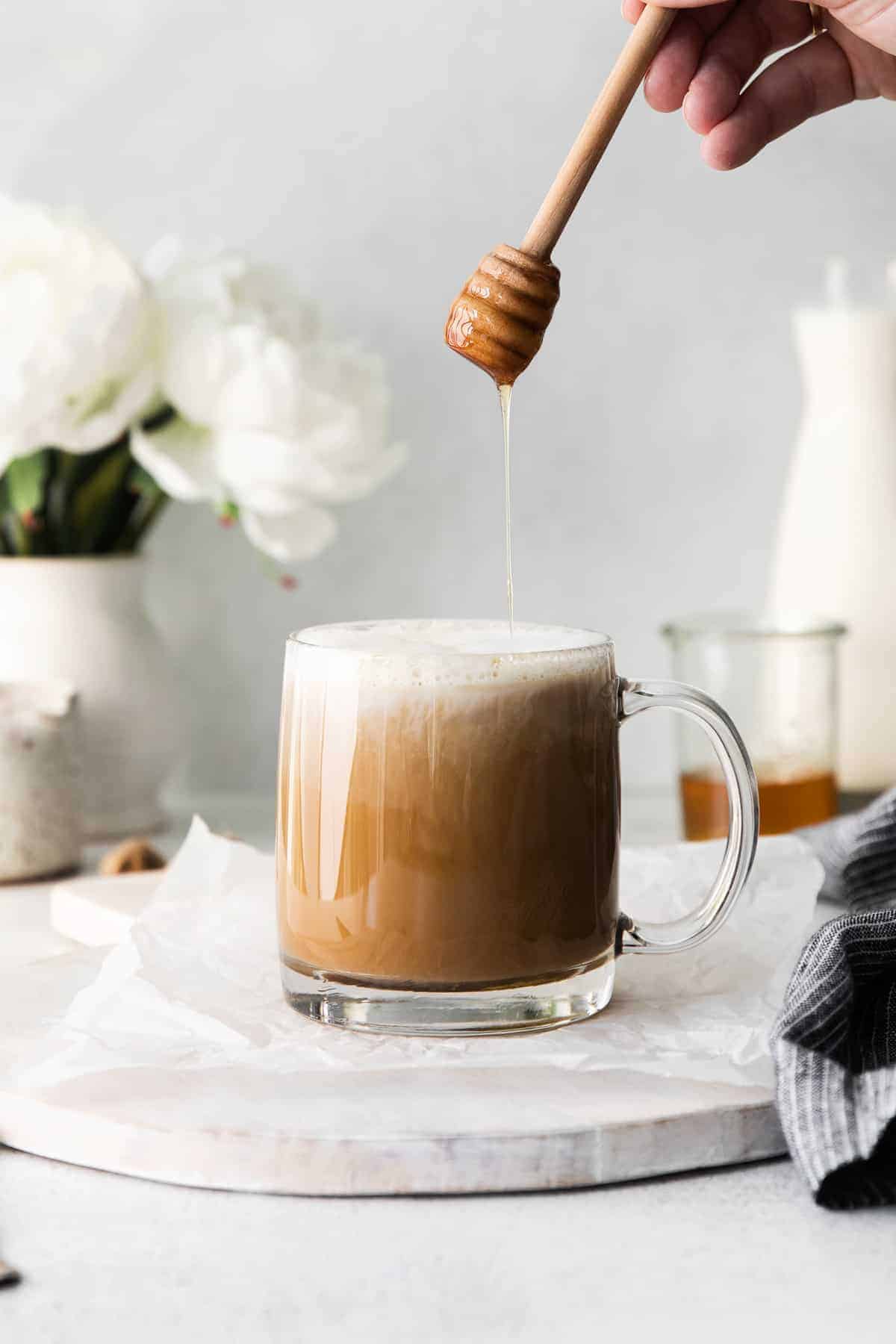 miel in a glass mug with a honey being drizzles on the top