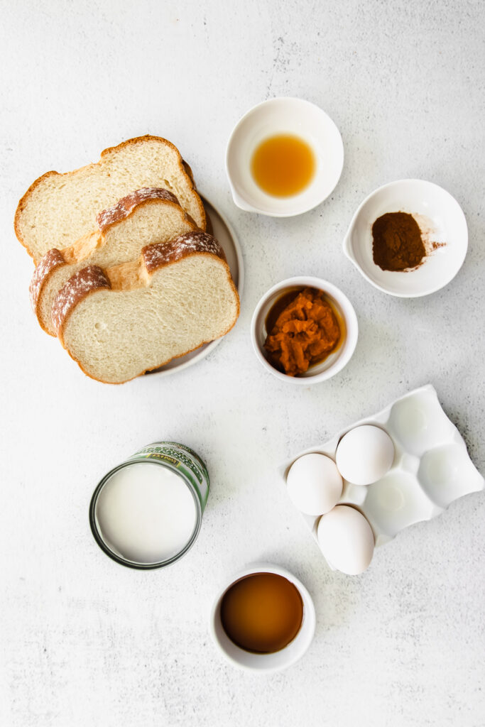 All the ingredients for pumpkin french toast in small bowls on the counter. 