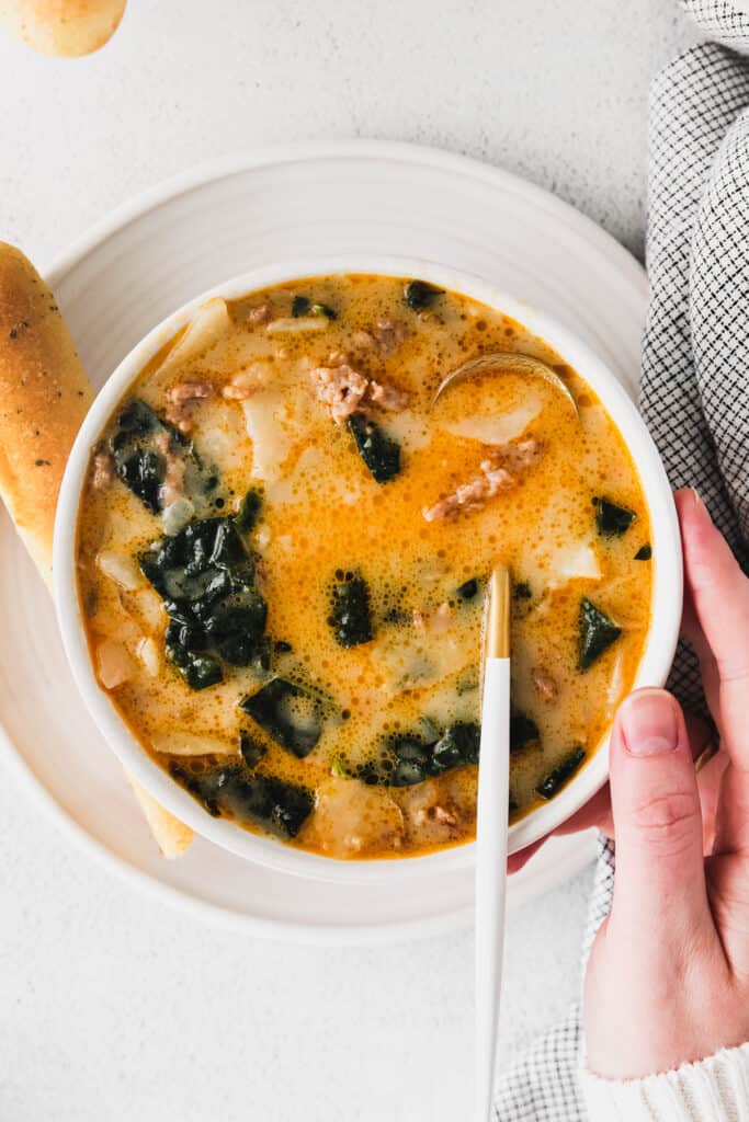 zuppa toscana soup in a bowl with a breadstick next to it