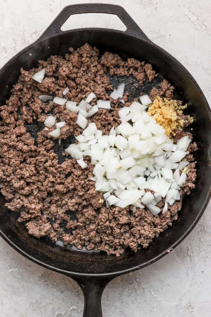 ground beef and diced onions in a cast iron skillet