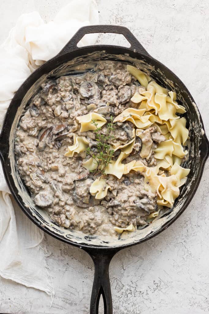 ground beef stroganoff in a cast iron skillet with egg noodles