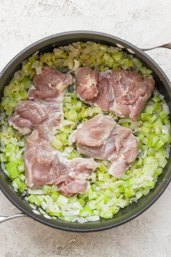 sauteed celery and onions in a dutch oven with chicken thighs