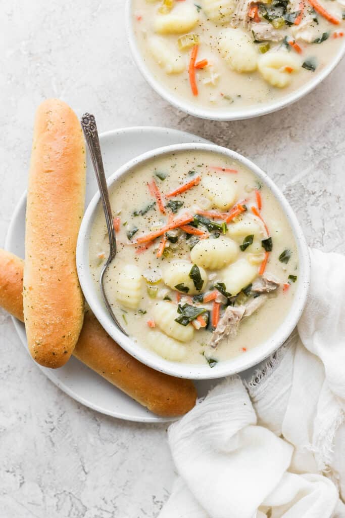 olive garden chicken gnocchi soup in a bowl next to a breadstick