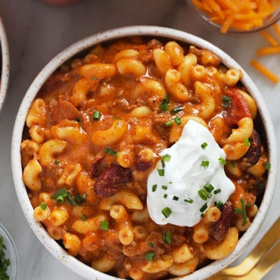 a bowl of chili macaroni and cheese with sour cream.