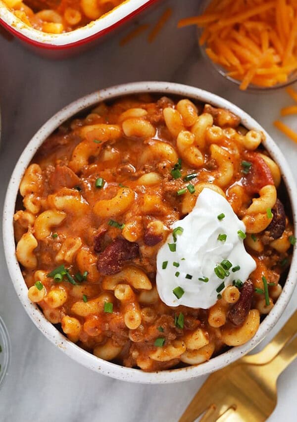 a bowl of chili macaroni and cheese with sour cream.