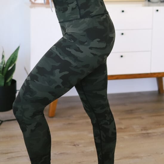 a woman wearing camouflage leggings in a living room.