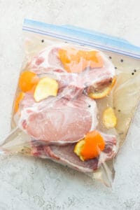 pork chops in a plastic bag with orange slices.