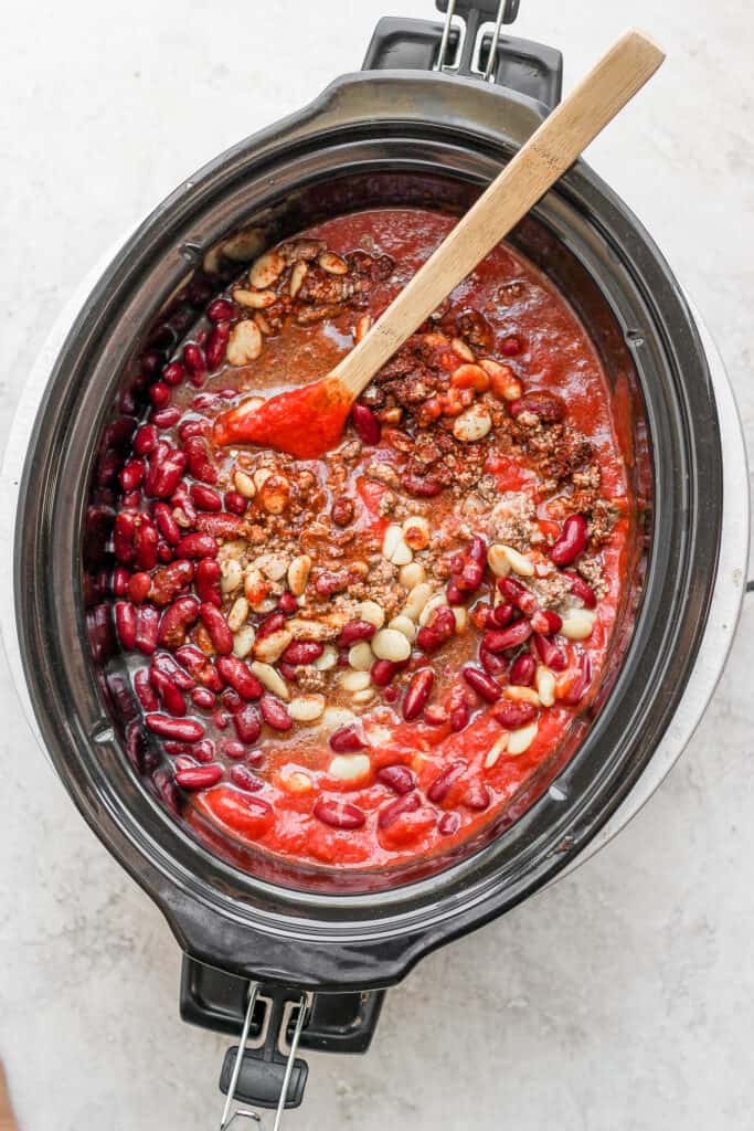 Slow cooker chili in a crock pot with a wooden spoon.