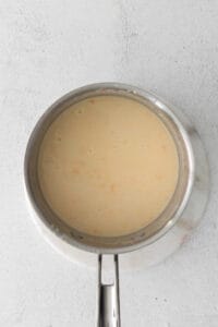 A pan with a sauce in it on a white surface.