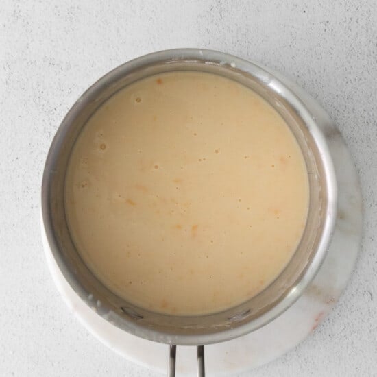 A pan with a sauce in it on a white surface.
