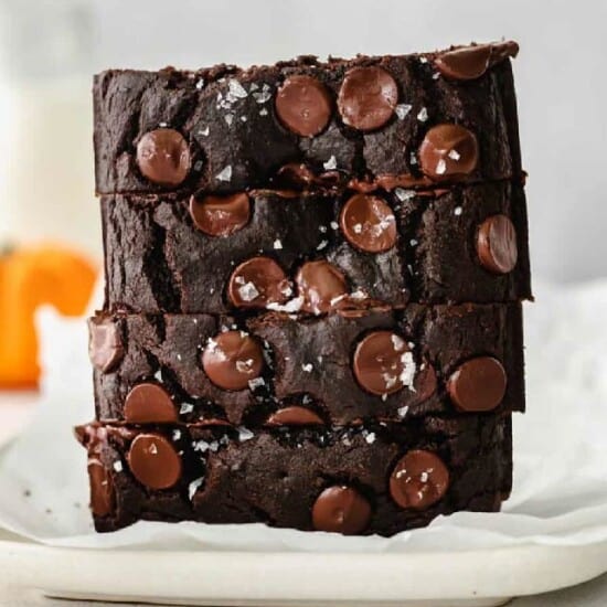 a stack of chocolate brownies on a white plate.