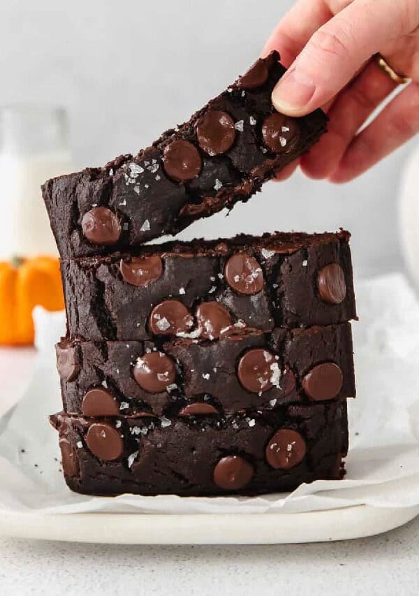 a person grabbing a slice of chocolate banana bread.